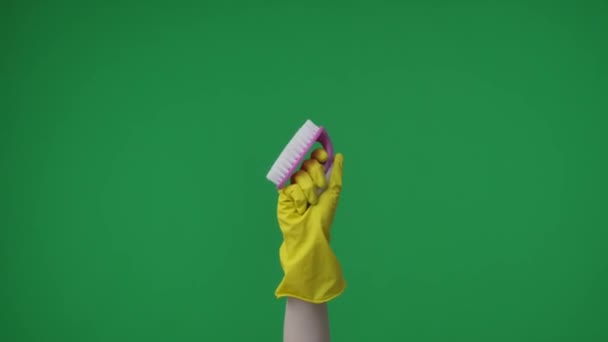 緑色の背景のフレームには 黄色いゴム製グローブのラメの女性の手が保持し ブラシを示しています クリーニングおよびクリーニング項目のために使用される ここにあなたの広告があるかもしれません 中型フレーム — ストック動画