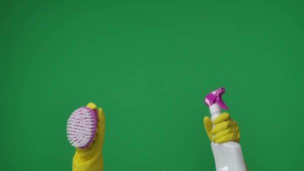緑色の背景のフレームでは ブラシと洗剤を保持している黄色いゴム製手袋のキーメイドの女性の手 クリーニングおよびクリーニング項目のために使用される ここにあなたの広告があるかもしれません 中型フレーム — ストック動画
