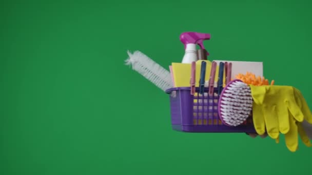 框架在绿色的背景 女用手伸出一篮子含有洗涤剂 手套和刷子的女人的手清洁物品时 她向摄像机递出一个盒子 — 图库视频影像