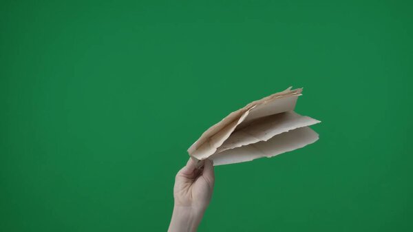 Рамка на зеленом фоне, хромаки. Женская рука с маникюром держит небольшую стопку смятых белых листов бумаги. Она держит их над собой лицом к камере. Средняя рамка