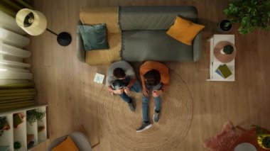 Kanepenin yanında yerde oturan homoseksüel bir çiftin en iyi görüntüsü. Bir adam ortağına hediye kutusu veriyor. Şefkatle sarılıyorlar. LGBT, eşitlik, eğitim içeriği, gurur.