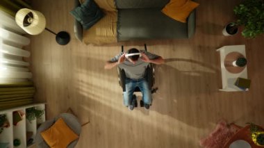 Top view engelli bir yetişkini, tekerlekli sandalyede oturan, kulaklık takan ve müzik dinleyen bir adamı çekiyor. Özürlülük, bağımsızlık ve