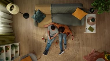 Evde homoseksüel bir çiftin en iyi görüntüsü. Yerde oturuyorlar, televizyon izliyorlar, abur cubur yiyorlar, ne izleyeceklerini seçiyorlar, sarılıyorlar ve birbirleriyle konuşuyorlar. LGBT, eşitlik, eğitim.