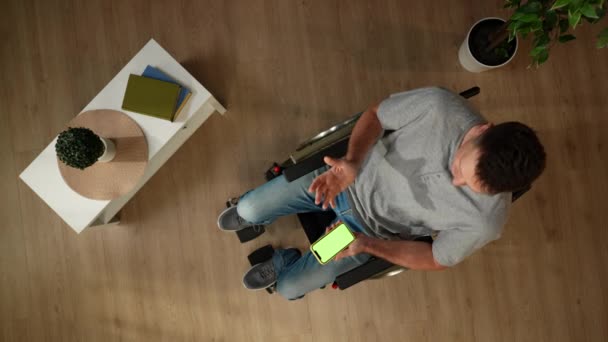 头像拍摄了一个行动障碍男子坐在轮椅上的房间 使用智能手机与广告区 工作空间模拟它 嘲笑的东西 包容性 — 图库视频影像