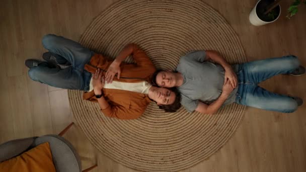 同性愛者 バイセクシャル パノラル トランスジェンダーのカップルが床に横たわり 目を開け 自由を奨励するためにカメラに微笑むトップビューショット 教育コンテンツ — ストック動画