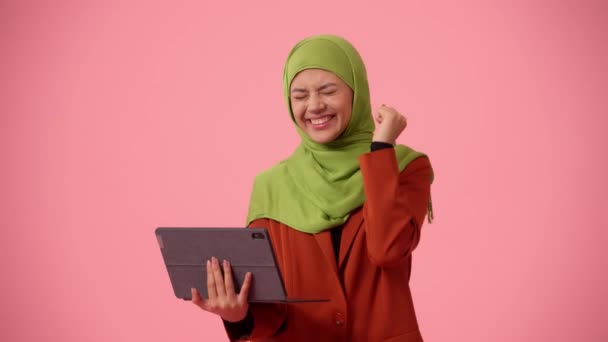 中等尺寸的独立录像拍摄了一个戴着头巾 头戴面纱的年轻貌美女子 她拿着一个平板电脑 笔记本电脑 对这个好消息很兴奋 文化多样性 就业和教育 — 图库视频影像