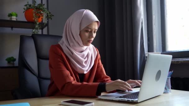 中等尺寸的视频拍摄了一个戴着头巾 头戴头巾的年轻貌美女子 她在一台笔记本电脑上工作 对她看到的东西感到困惑 文化多样性 就业和教育 — 图库视频影像