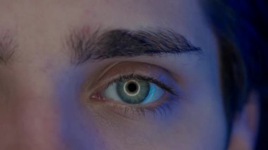 Genç bir adamın gözü makro atış. Akıllı telefondan gelen mavi ışık, erkeğin gözlerine yansıyan bilgisayar ekranı. Sağlık kavramı