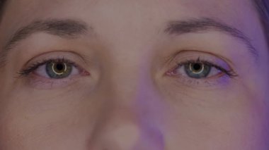 Genç bir kadının gözleri makro çekim yapıyor. Akıllı telefondan mavi ışık, kadınların gözlerine bilgisayar ekranı yansıyor. Sağlık, güzellik ve bakım kavramı