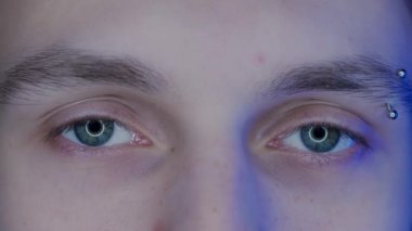 Kaş delici makro vuruşlu genç adamın gözleri. Akıllı telefondan gelen mavi ışık, erkeğin gözlerine yansıyan bilgisayar ekranı. Gadget suistimali kavramı