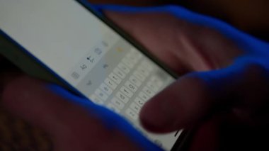 Akıllı telefonlu bir mesaj. Bir adam telefonundan bir mesaj gönderir, onu kapatır ve bir kenara bırakır. Dijital anlık mesajlaşma sohbeti. Klavye ve parmak yazmanın makro görüntüsü. Görüşme