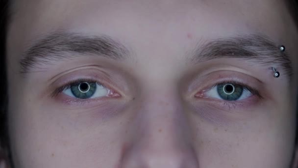 マクロショットを貫通した眉毛の若い男の目 ガジェットの長期使用による拡大された生徒 ドライアイ症候群 健康コンセプト — ストック動画