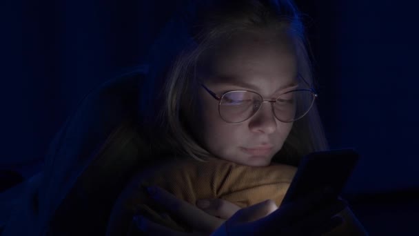 Jovem Com Óculos Está Enviando Mensagens Seu Smartphone Deitado Cama — Vídeo de Stock