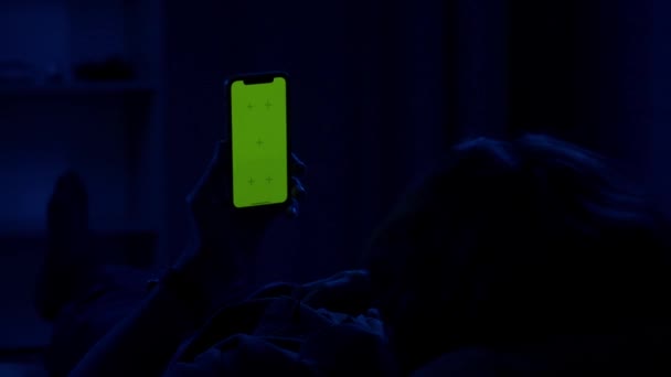 Мужчина Лежащий Ночью Диване Зеленым Экраном Руках Мужчина Смотрит Видео — стоковое видео