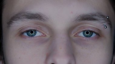 Kaş delici makro vuruşlu genç adamın gözleri. Cihazların uzun süre kullanılmasından dolayı büyümüş gözbebekleri. Kuru göz sendromu. Sağlık kavramı