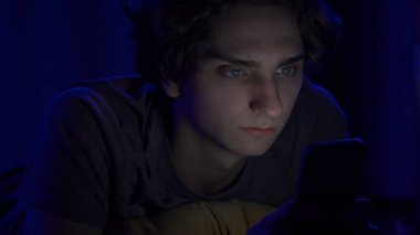 Genç bir adam akıllı telefonuyla mesaj atıyor. Geceleri yatakta yatıp kapatıyor. Teknoloji, internet, iletişim ve insan kavramı