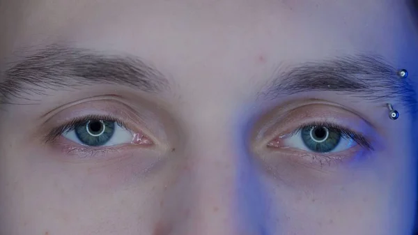 マクロショットを貫通した眉毛の若い男の目 スマートフォンからのブルーライト コンピュータ画面が大人の目に反映されます ガジェット虐待の概念 — ストック写真