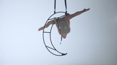 Ritmik jimnastikçi kız, metal bir yapı uydusunda tek koluyla havadaki pisliği canlandırıyor. Beyaz arkaplan