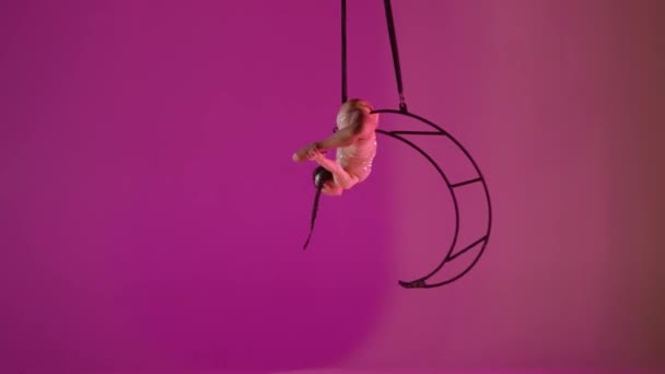 リズミックジムナスティックガールは 金属回転構造ムーンピンクの背景上の空気中の片腕のスカムを実行します — ストック動画