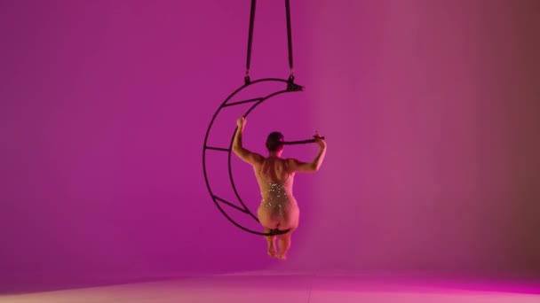 在金属旋转结构的月亮粉红背景下 体操女子在空中一只胳膊上表演人渣 — 图库视频影像