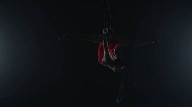 Ritmik jimnastikçi kız, metal bir yapı uydusunda tek koluyla havadaki pisliği canlandırıyor.