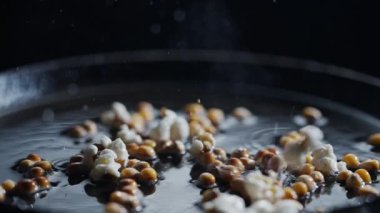 Patlamış mısır kızartma tavasında pişirilir. Arka planda ayçiçeği yağı ile yüksek hızlı kamerayla çekilir..
