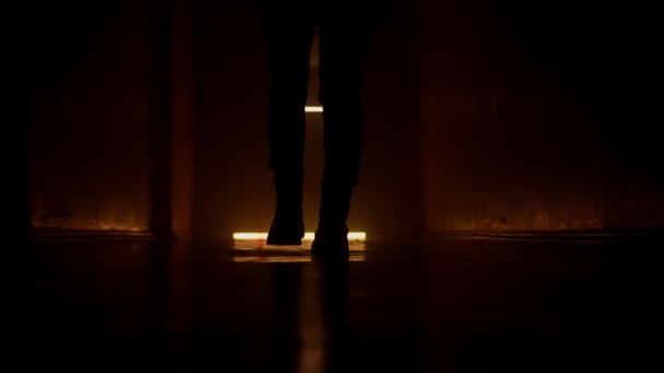 シルエットの女性は暗い廊下を歩いています 低地から撮影 オレンジライト — ストック動画