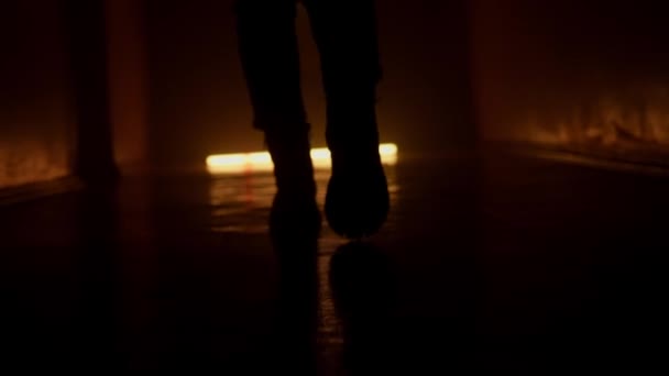 暗い廊下を歩く冬のブーツの足のシルエット オレンジライト — ストック動画