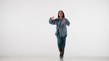 Beyaz, açık arkaplanda. Genç ve güzel bir kızla dans ediyor. Hip hop tarzında dans hareketleri gösteriyor. Kameraya bakıyor. Rahat kıyafetler giyiyor. Ritmik..