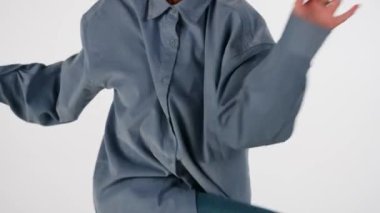 Beyaz, açık arkaplanda. Genç ve güzel bir kızla dans ediyor. Hip hop tarzında dans hareketleri gösteriyor. Kameraya bakıyor. Rahat kıyafetler giyiyor. Ritmik..