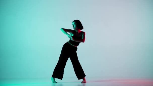 ブルーのフレームで ライトバック 若くて美しい女の子を踊る ヒップホップのスタイルでダンスの動きを示しています カメラを見つめている影 黒いトップとズボンのシェイスフェミニン — ストック動画