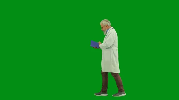 保健和健康创新概念 彩色键绿色屏幕上的演播室男医生画像 身穿白色制服的资深医生在日记中阅读文件 侧视图 — 图库照片
