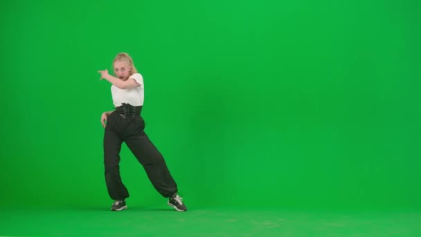 緑色の背景にあるフレームでは 染色体 若くて細く 美しい女の子が踊っている 彼女はジャズファンクの方向にさまざまなダンスの動きを示しています 彼女はリズム的でプラスチック的だ 一般プラン — ストック動画