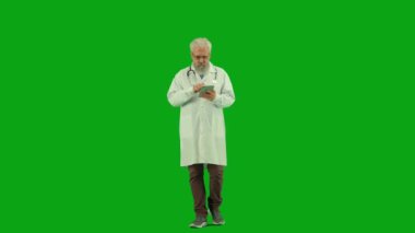 Sağlık ve tıbbi danışmanlık reklam konsepti. Krom anahtar yeşil ekranda yaşlı doktor portresi. Üniformalı kıdemli doktor elinde tablet, internetten bilgi arıyor..