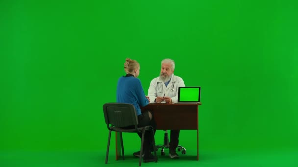 医療コンサルティング広告コンセプト クロマ グリーン スクリーンの老人の薬の肖像画 女性患者と話すテーブルのシニアドクター ラップトップに表示 ワークスペースモックアップ — ストック動画