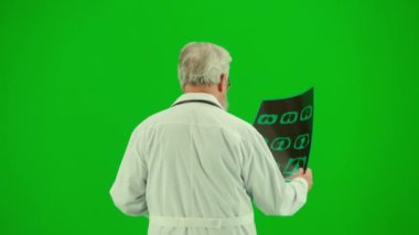 Sağlık ve tıbbi danışmanlık reklam konsepti. Krom anahtar yeşil ekranda insan sıhhiyesinin portresi. Arkaya bakın. Üniformalı kıdemli doktor elinde x-ray 'le yürüyor..