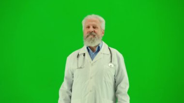 Sağlık ve tıbbi danışmanlık reklam konsepti. Krom anahtar yeşil ekranda insan sıhhiyesinin portresi. Beyaz önlüklü kıdemli doktor kameraya kollarını kavuşturup gülümsüyor..