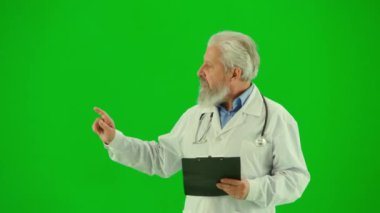 Sağlık ve tıbbi danışmanlık reklam konsepti. Krom anahtar yeşil ekranda insan sıhhiyesinin portresi. Beyaz önlüklü kıdemli doktoru kapatın. Pano ile reklam için bölgeyi gösteriyor.