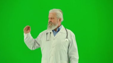 Sağlık ve tıbbi danışmanlık reklam konsepti. Krom anahtar yeşil ekranda insan sıhhiyesinin portresi. Beyaz önlüklü kıdemli doktor reklam için boş yer gösteriyor, gülümsüyor..