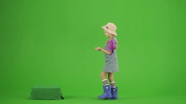 Bahçıvanlık ve tarım reklamları konsepti. Krom anahtar yeşil ekranda şapkalı ve lastik çizmeli bir kızın portresi. Küçük tatlı bahçıvan kız tohum döker toprağa Ümit dolu ve mutlu görünür.