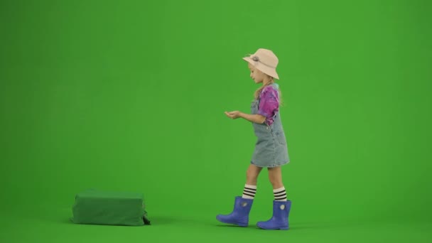 ガーデニングと農業の広告コンセプト クロマ グリーン スクリーンの帽子およびゴム製ブーツの少女の肖像画 小さなかわいいガールガーデンガーデナーは 驚いたように見える土壌に肥料を提供します — ストック動画