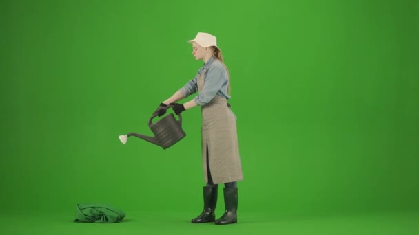 园艺和农业广告的概念 女性穿着围裙和橡胶靴的肖像出现在色键绿色屏幕上 女园丁站在那里 拿着浇灌罐和浇灌植物 微笑着 — 图库视频影像