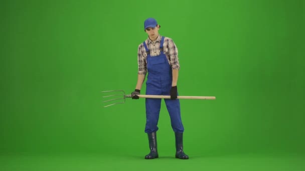 ガーデニングと農業の広告コンセプト クロマキーグリーンスクリーンに男性とゴムブーツの肖像画 男の庭師は手でピッチフォークを保持し 疲れているように立っています — ストック動画