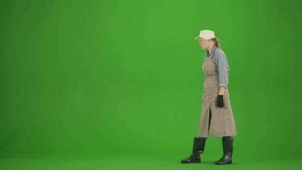 园艺和农业广告的概念 女性穿着围裙和橡胶靴的肖像出现在色键绿色屏幕上 女园丁站在那里看着她的植物 积极向上的表情 — 图库视频影像