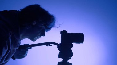 Stüdyoda çalışan profesyonel erkek fotoğrafçı. Renkli neon ışık kullanıyor.