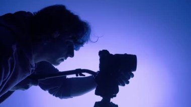 Stüdyoda çalışan profesyonel erkek fotoğrafçı. Renkli neon ışık kullanıyor.