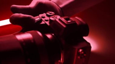 Profesyonel fotoğraf makinesi, renkli neon ışıklı bir stüdyoda tripodun üzerinde duruyor. Çekimler başlamadan önce fotoğrafçı ayarları yapar.