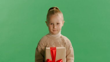 Stüdyodaki sarı arka plan duvarına izole edilmiş bir şekilde poz veren küçük şirin bir kız çocuğu. Noel konsepti.