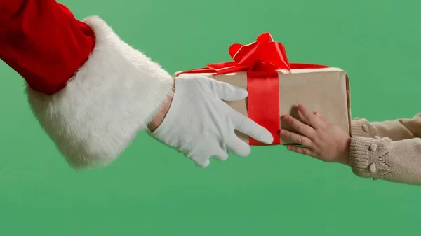 Santa hands handing a gift to a little girl against a green screen background.