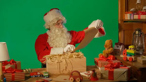 Noel Baba Hediyelerle Masada Yeşil Bir Arkaplanda Bir Mektup Paketi — Stok fotoğraf